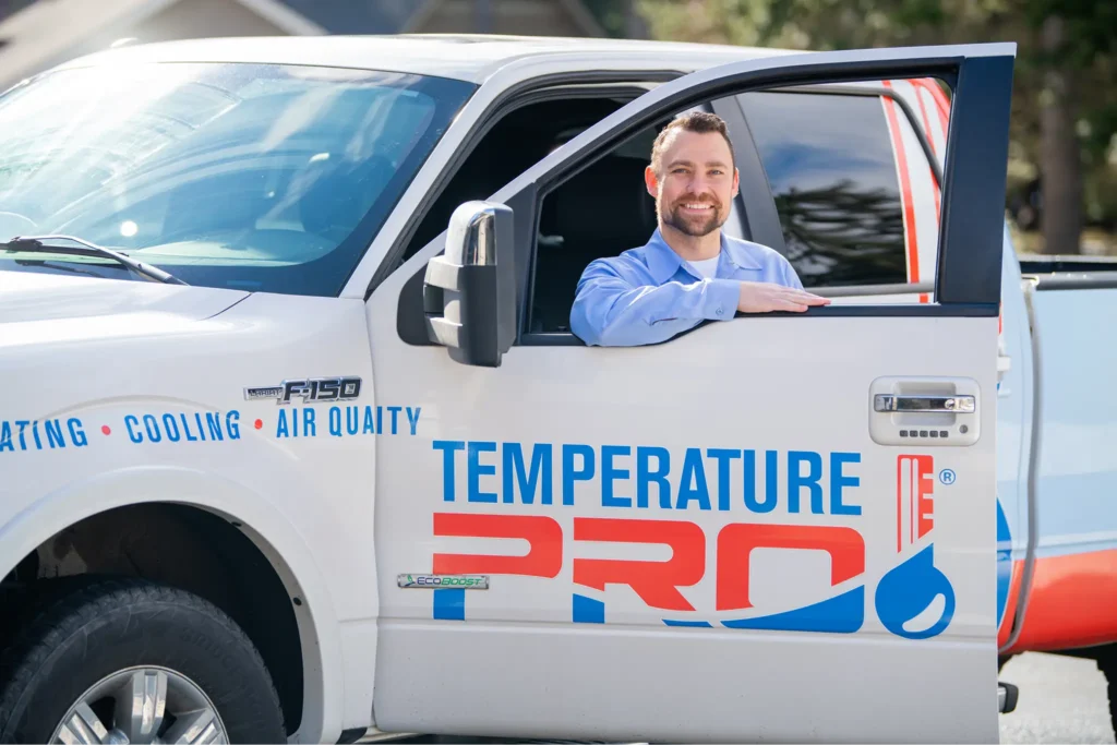 used (14) 1 TemperaturePro Mokena heating tune-up technician standing in the door of service vehicle.