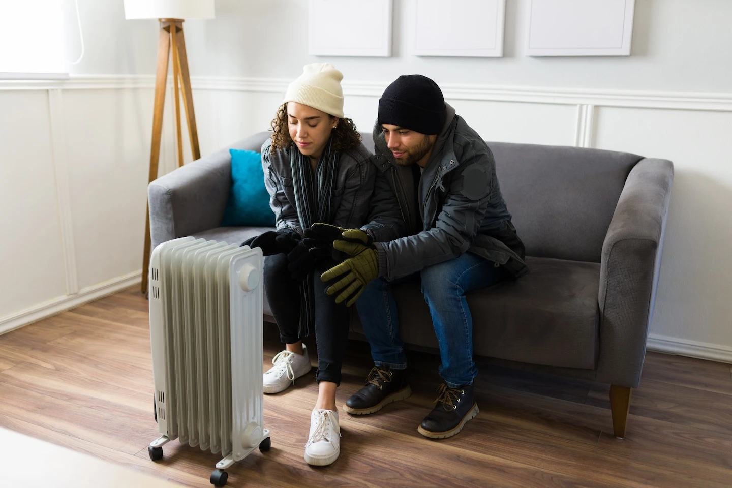 A young couple huddles next to a heater for warmth. 