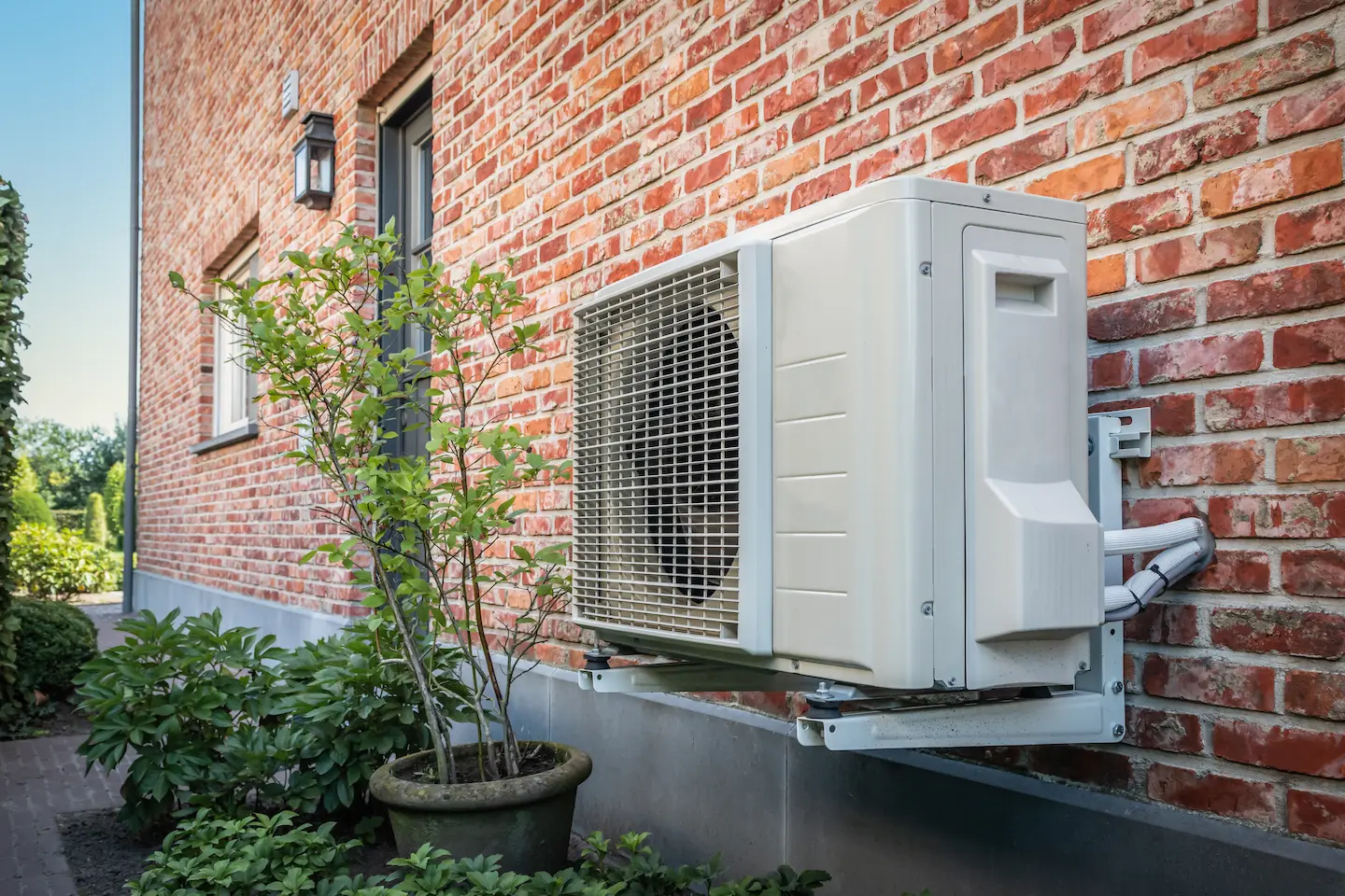 Outdoor air conditioning unit mounted on brick home exterior