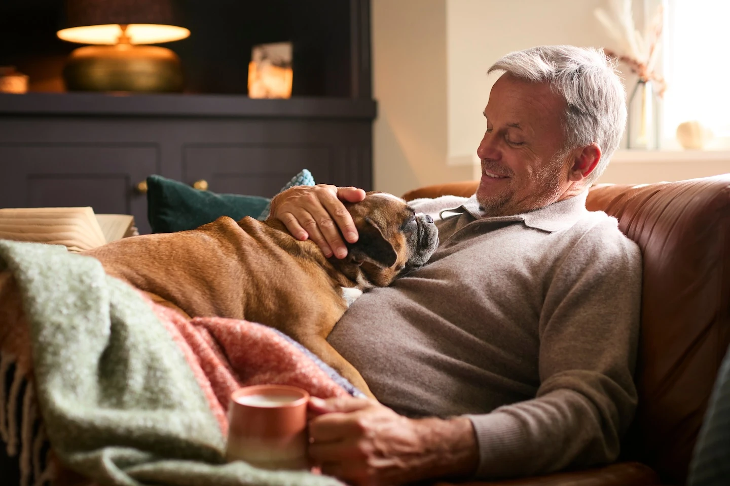 Man relaxing on a couch with his dog in a warm living room