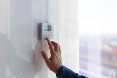 Hand adjusting a digital wall thermostat